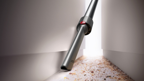 Using a crevice tool to vacuum up dirt between two cabinets.